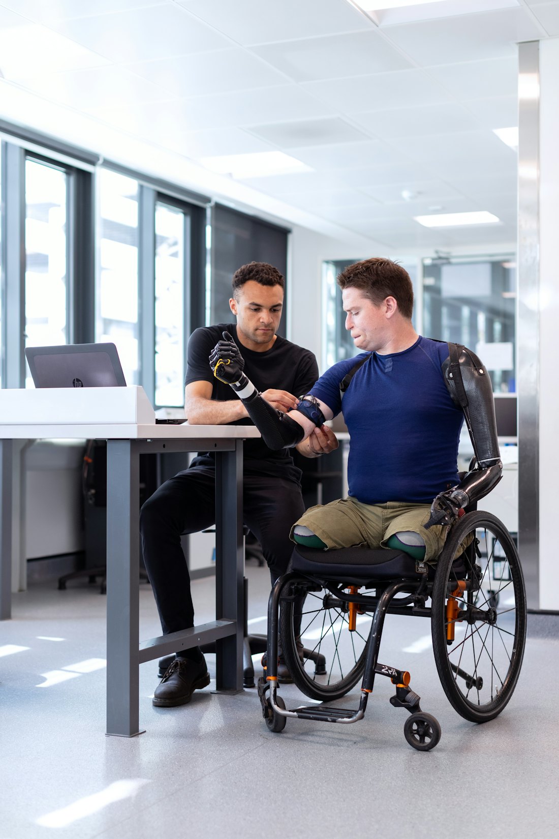 A man in a wheelchair with a prosthetic arm working in a lab