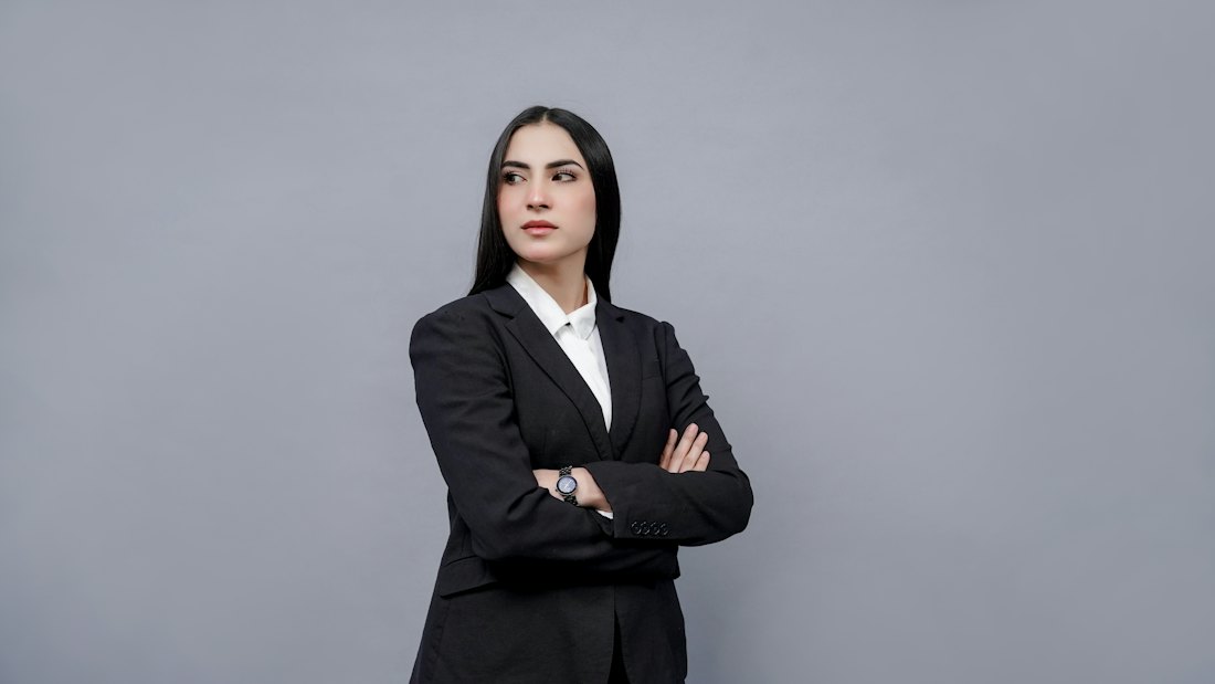 A woman in a dark business suit standing with her arms crossed